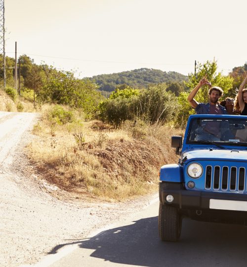 Friends in an open car, passengers standing in the back