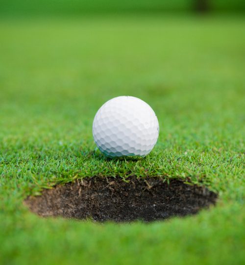golf ball on lip of cup.  Golf ball and hole