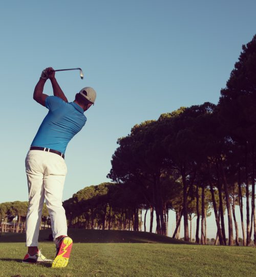 handsome sporty man, golf player hitting shot with club on course at beautiful morning