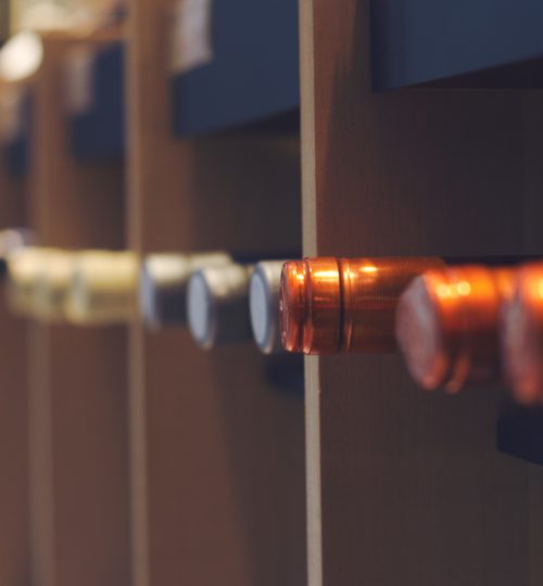perspective view closeup row wine bottles caps arranged in rack in supermarket shelf with selective focus